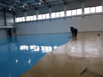 Aplicator Atess aplicând stratul final pe o pardoseală interioară